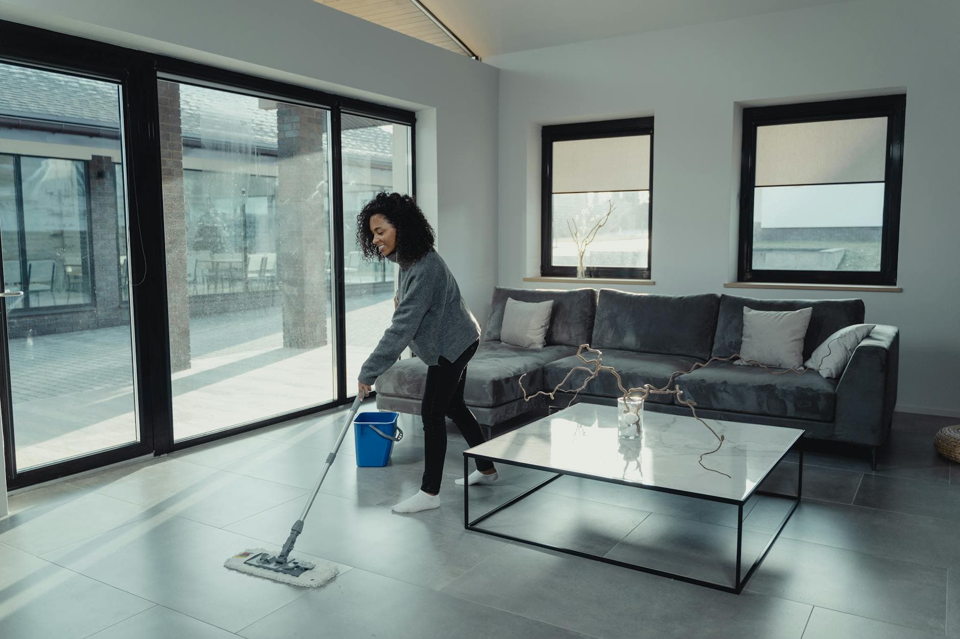 House cleaner mopping a bright, modern NYC apartment with large windows — cleaning services in Baychester, Bronx