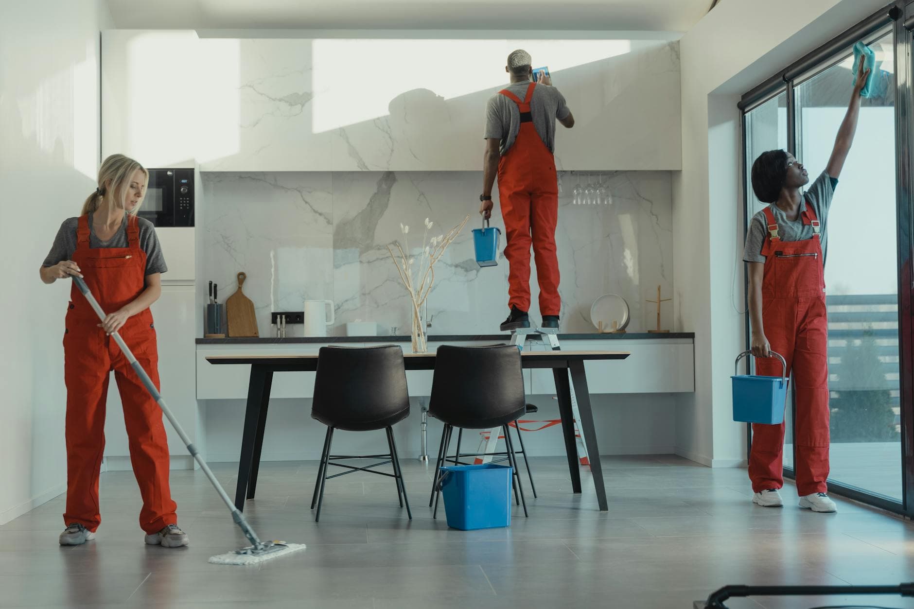 Your Business cleaning crew in red uniforms mopping and wiping glass in a New York dining room — Office Cleaning in Edgewater, New Jersey