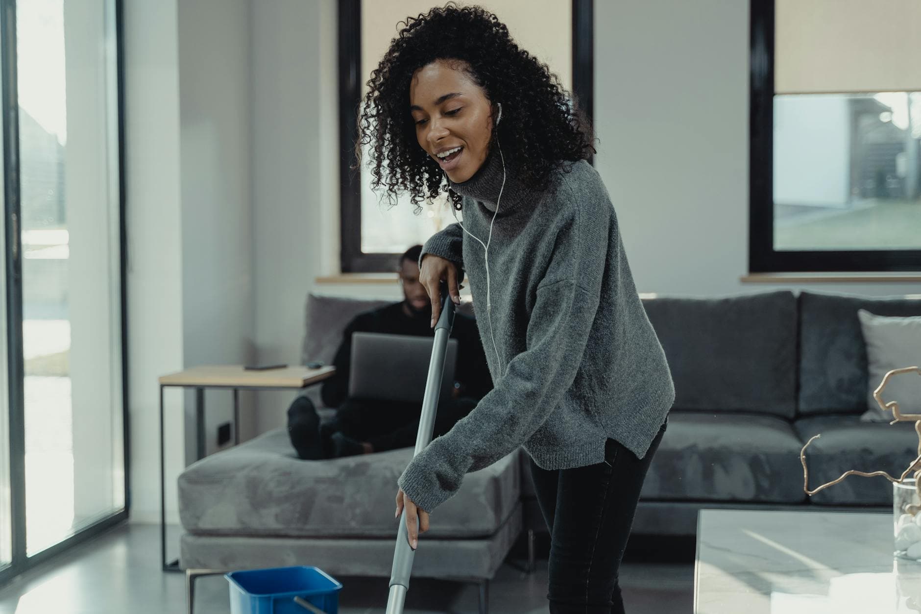 A professional house cleaner mopping the floor of a cozy New York City living room — Regular Apartment Cleaning in Douglaston, Queens