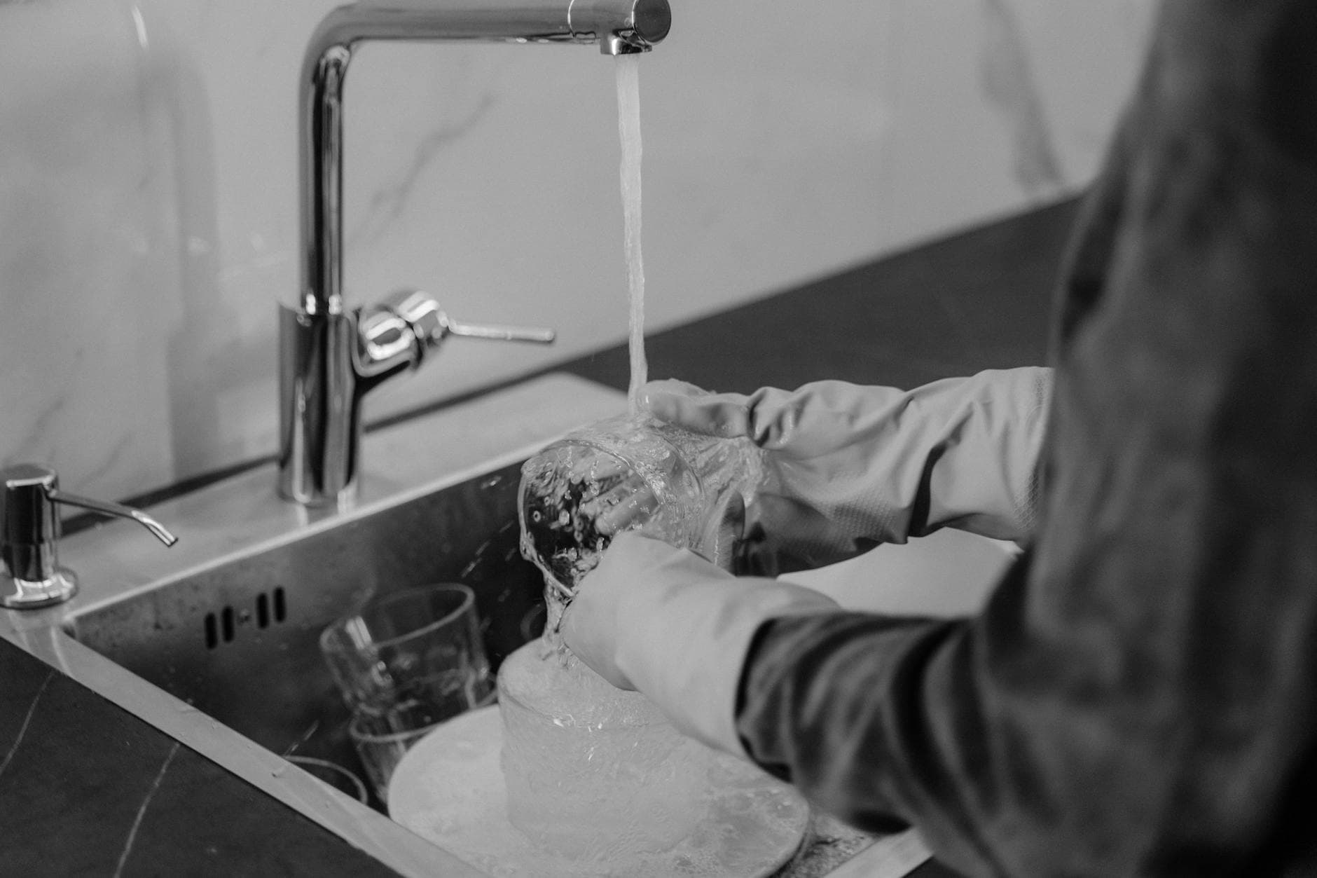 NYC kitchen cleaning service washing dishes under running water at the sink — Deep Cleaning in Floral Park, Queens