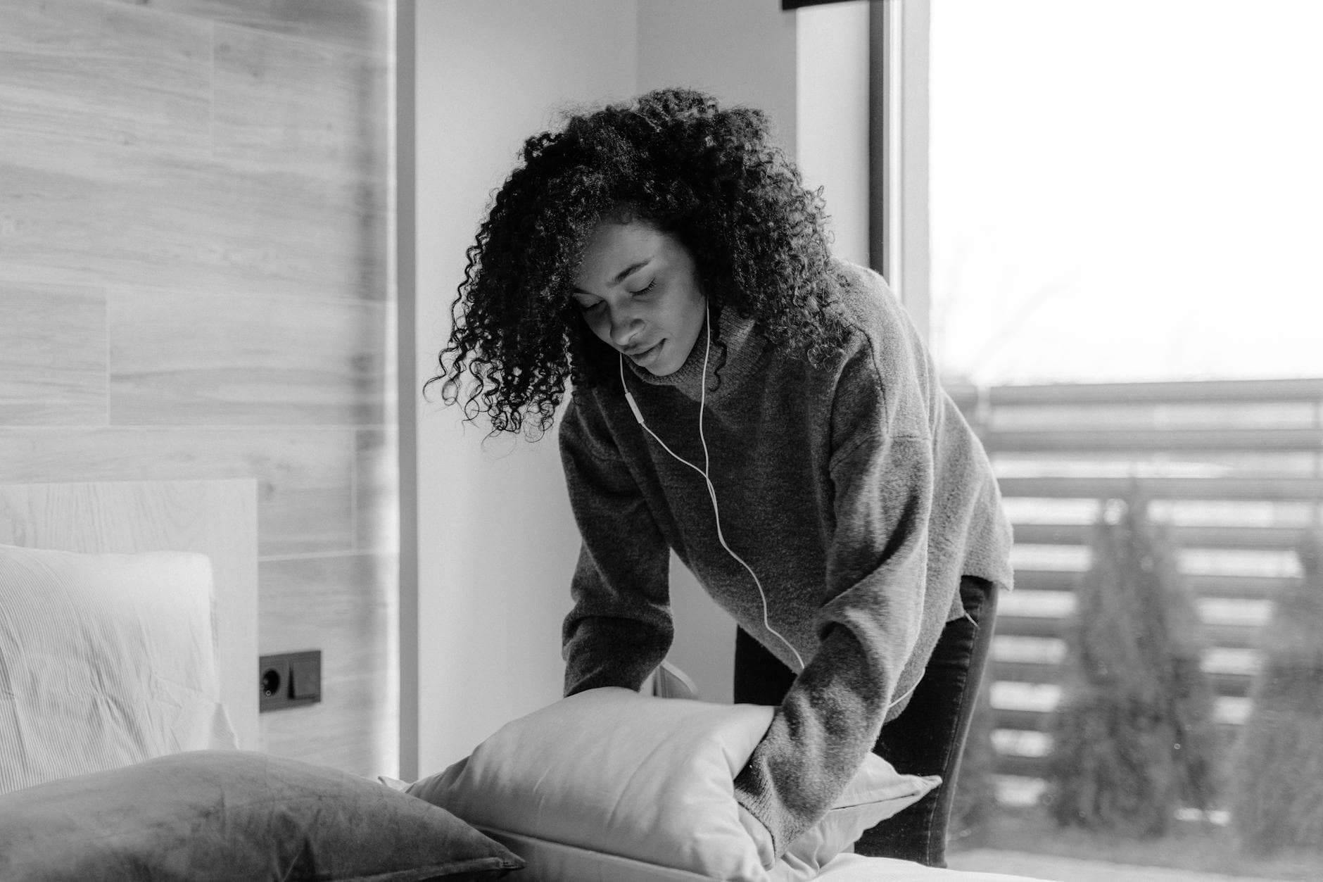 NYC maid service making the bed in a bright, monochrome bedroom — cleaning services in Guttenberg, New Jersey