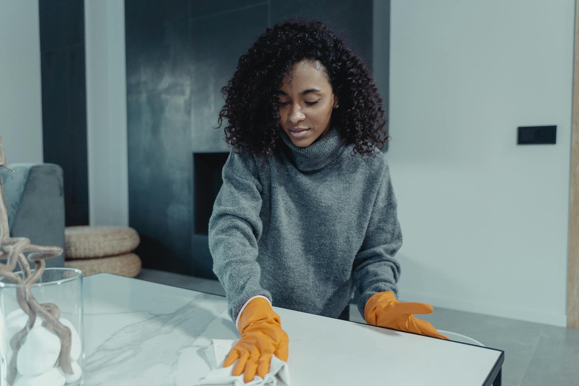 A NYC maid wearing gloves wiping a coffee table in a modern Manhattan living room — Bi-Weekly Cleaning in Cobble Hill, Brooklyn